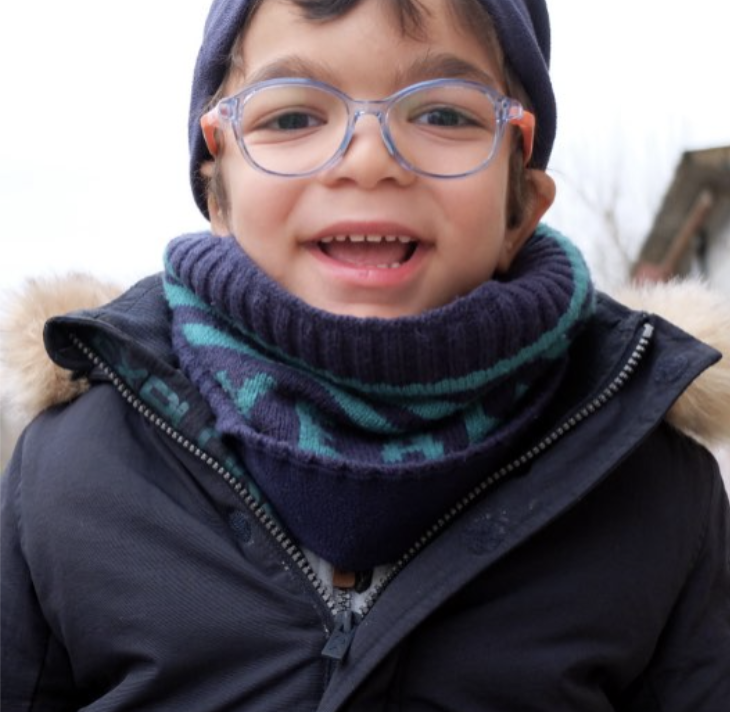 Jor wears blue glasses and smiles at camera